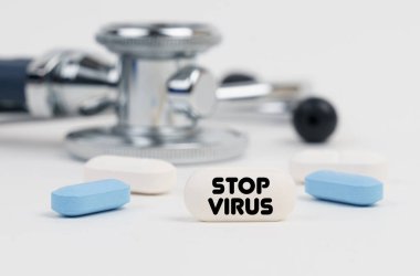Tıp ve sağlık konsepti. Beyaz bir yüzey yalan hapları, steteskop ve üzerinde DUR VIRUS yazan bir tablet.