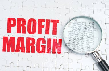 İş konsepti. Bulmacanın üzerinde bir büyüteç var, hemen yanında - PROFIT MARGIN