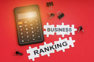 Finans ve ekonomi kavramı. Kırmızı yüzeyde bir hesap makinesi, klempler ve bulmacalar yazılı - İŞ ÇALIŞMA