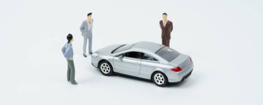 Endüstri ve ulaşım kavramı. Beyaz bir yüzeyde arabaya bakan insanların minyatür figürleri var..