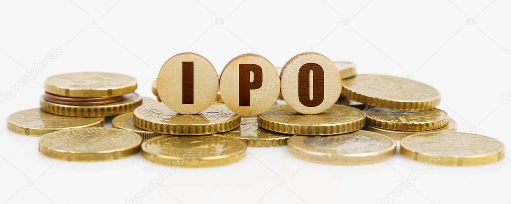 Business and finance concept. On a white surface lie coins and wooden circles with the inscription - IPO