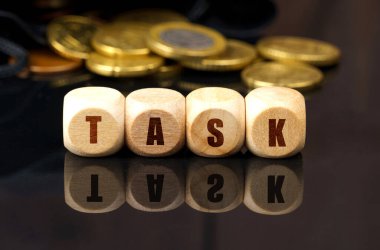 İş ve ekonomi kavramı. Siyah yansıtıcı yüzeyde, üzerinde yazı olan madeni paralar ve tahta küpler vardır. -