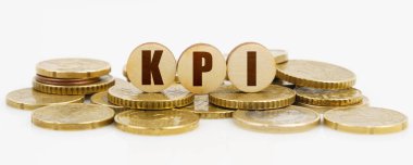 İş ve finans kavramı. Beyaz bir yüzeyde KPI yazılı paralar ve ahşap daireler bulunur.