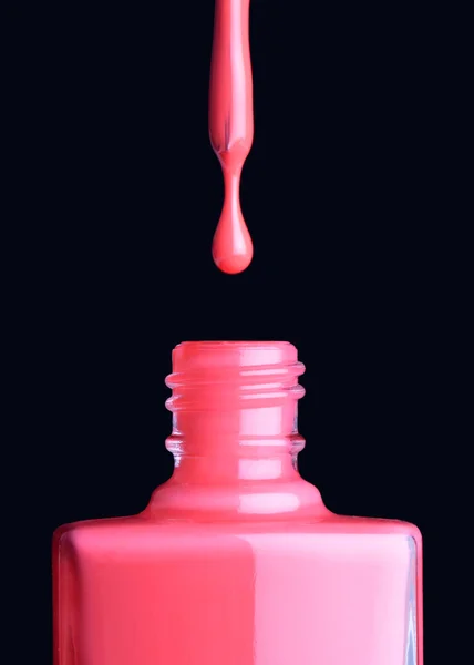 Nail varnish dripping from brush into bottle on black background — Stock Photo, Image