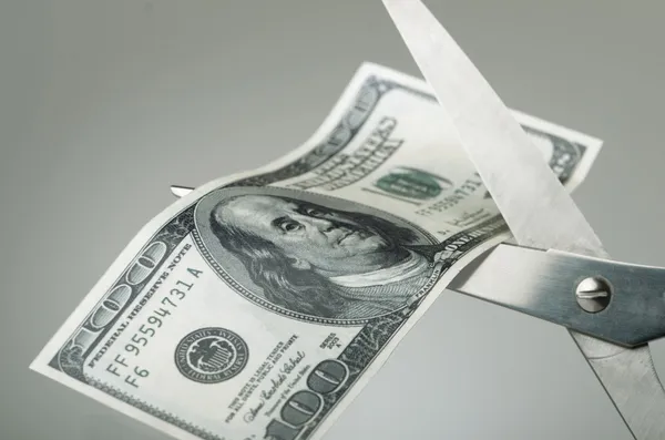 Scissors cutting a dollar bill in half — Stock Photo, Image