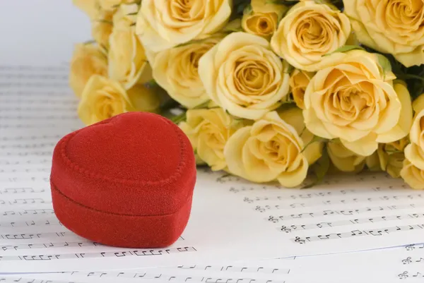 Rosas amarelas e uma caixa segurando anéis de casamento com fundo musical — Fotografia de Stock