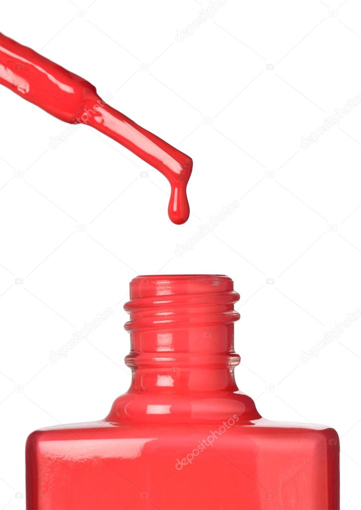 Nail varnish dripping from brush into bottle on white background
