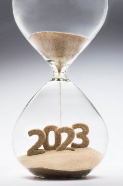 New Year 2023 concept with hourglass falling sand taking the shape of a 2023