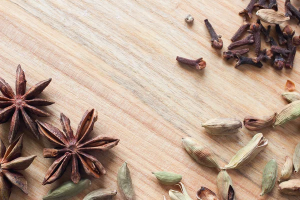 Wooden background texture with aromatic spices. Star anise, cardamom and cloves for cooking — Stock Photo, Image