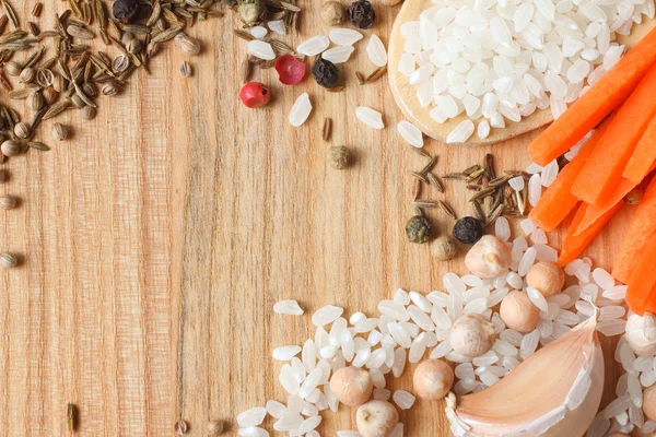 Reis, Kichererbsen, Karotten und Gewürze für Pilaf auf Holzgrund — Stockfoto