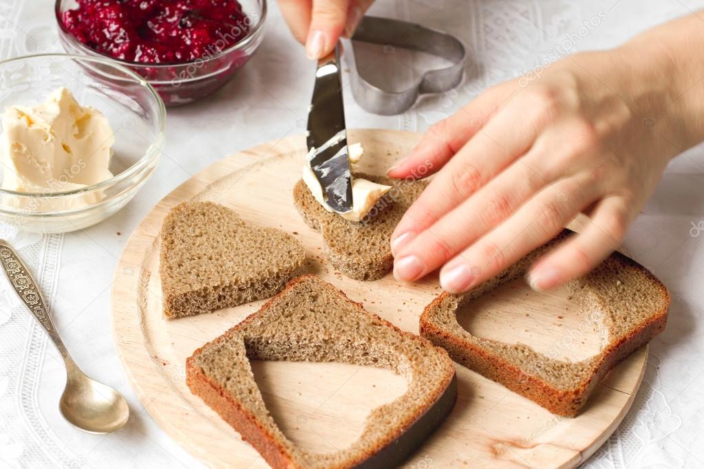 Cutting hearts from bread with butter