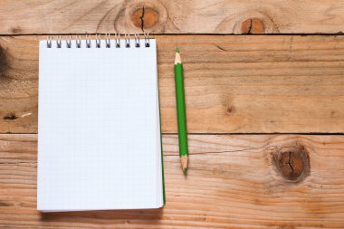 ahşap masa üzerinde yeşil kalem ile defter