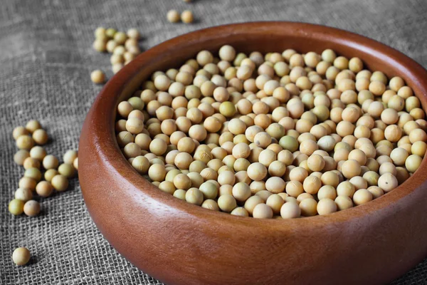 Soybeans in wooden bowl on linen sackcloth — Stock Photo, Image