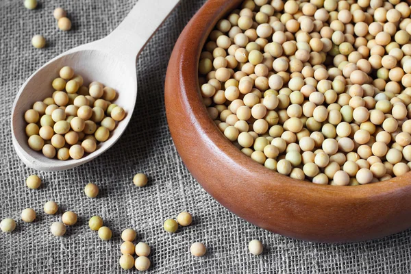 Soybeans in wooden bowl on linen sackcloth with wooden spoon — Stock Photo, Image