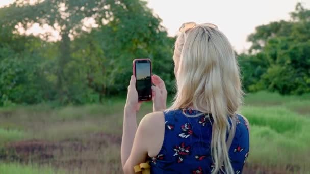 A woman is making a photos of sunset – Stock-video