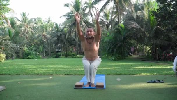 A middle-aged man practices yoga. Morning, public park, Asia. — Stockvideo