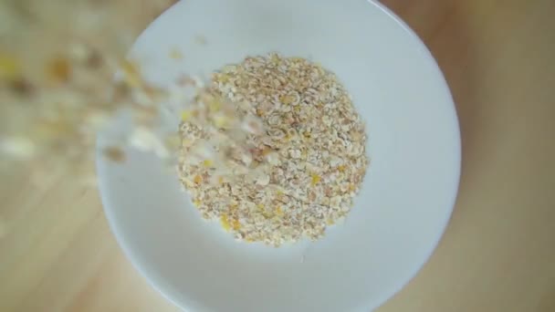 Oatmeal is poured into a bowl. Wholesome breakfast preparation — Vídeo de Stock