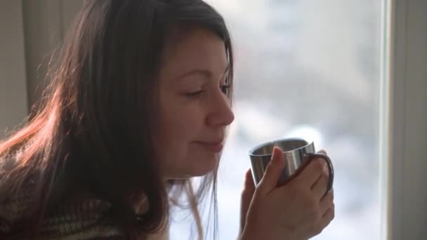 A menina olha pela janela e bebe café. Mulher atenciosa — Vídeo de Stock