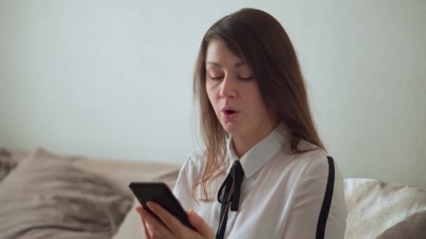 Το κορίτσι χρησιμοποιεί ένα smartphone. Διεξάγει την αλληλογραφία σε έναν δημοφιλή αγγελιοφόρο. — Αρχείο Βίντεο