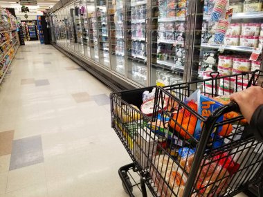 Wilmington, Delaware, U.S.A - January 8, 2022 - Pushing a cart filled with groceries on the empty frozen aisle inside a supermarket