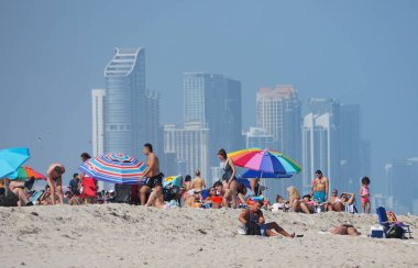 Miami Beach, Florida, ABD - 18 Şubat 2022 Miami şehir merkezine bakan plajda dinlenen ziyaretçiler