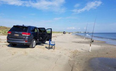 Broadkill Plajı, Delaware, ABD - 16 Mayıs 2022 - Sahilde surfishing çubuklarına bakan bir Jeep Cherokee