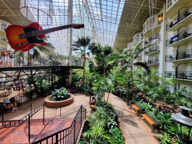Nashville, Tennessee, U.S.A - June 26, 2022 - The walking path and a large guitar by tropical plants inside of Gaylord Opryland Resort and Convention Center