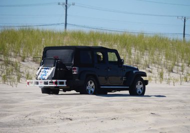 Dewey Beach, Delaware, U.S.A - August 13, 2022 - A back Jeep Wrangler driving on the beach