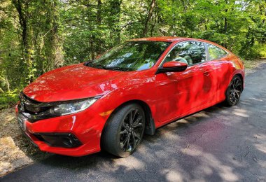 Caroll County, Arkansas, U.S.A - June 23, 2022 - A bright red 2021 Honda Civic parked by the woods