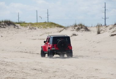 Dewey Beach, Delaware, U.S.A - September 3, 2022 - A red Jeep Wrangler driving on the beach