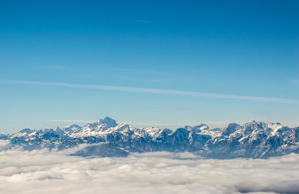 Bulutların üstünde kar kaplı dağ zinciri — Stok fotoğraf