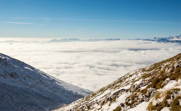 Bulutların üstünde kar yamaçları kaplı — Stok fotoğraf