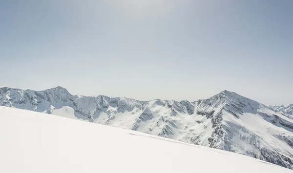 Declive coberto de neve com cume de montanha na parte de trás — Fotografia de Stock