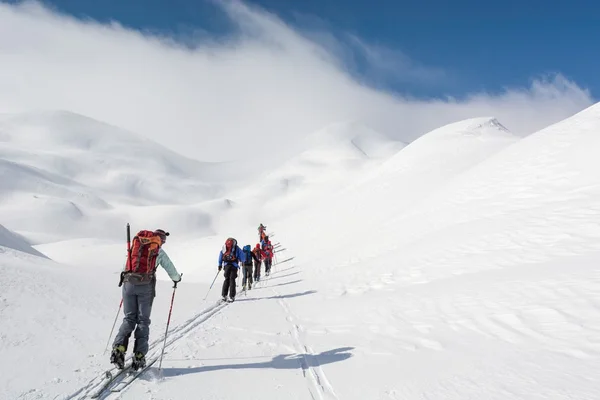 Skidåkare gående mot bergen — Stockfoto