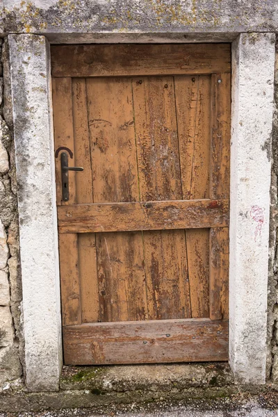 Oude houten deur in een muur — Stockfoto
