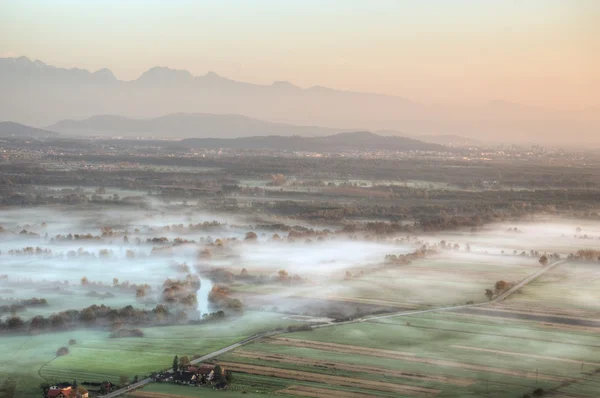 Lever de soleil au-dessus des champs couverts de brumes matinales — Photo