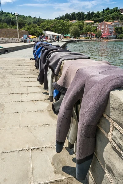 Trajes de buceo secándose en una pared de ladrillo — Foto de Stock