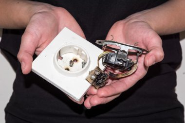 hasarlı bir elektrik prizine tutan kişi