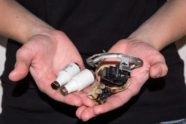 Person holding a damaged electric socket with a pair of fuses — Stock Photo, Image