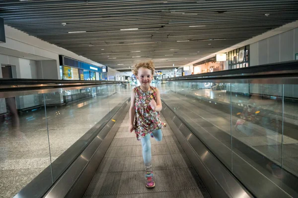 Cute blondynka dziewczyna działa na prędkości schodów ruchomych na lotnisku. — Zdjęcie stockowe