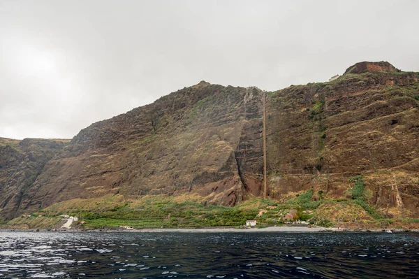 Panoramic view of sheer volcanic cliff rising above ocean. — Stock Photo, Image