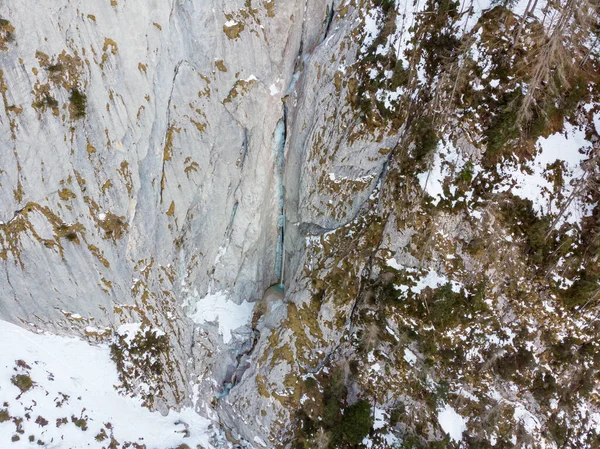 Vue aérienne spectaculaire de chutes d'eau gelées tombant sur une corniche rocheuse en hiver. — Photo