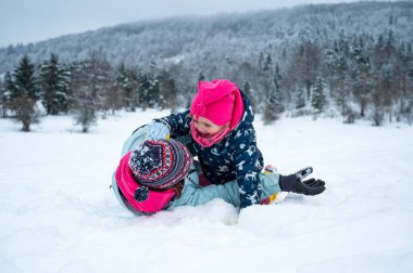Anne ve kızı karda eğleniyor.