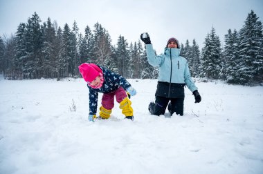 Anne ve kızı kar topu atarak eğleniyorlar..