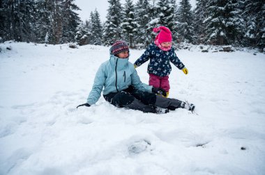 Anne ve kızı karda eğleniyor.
