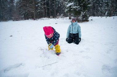 Anne ve kızı kar topu atarak eğleniyorlar..