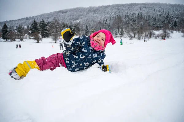 Linda chica posando en nieve fresca tumbado y saludando. — Foto de Stock