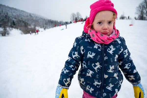 Droevig meisje met roze hoed op besneeuwde helling. — Stockfoto