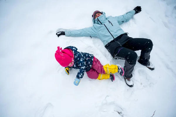 Anne ve kızı birlikte kar meleği yapıyorlar.. — Stok fotoğraf