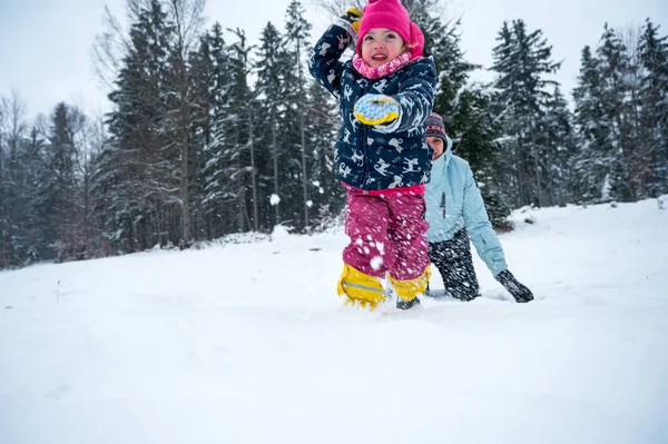 Moeder en dochter hebben plezier maken en gooien sneeuwballen. — Stockfoto